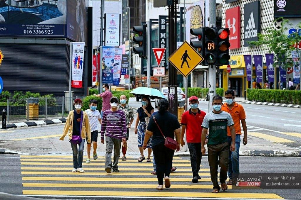 Pedestrians cross a road in downtown Kuala Lumpur.
