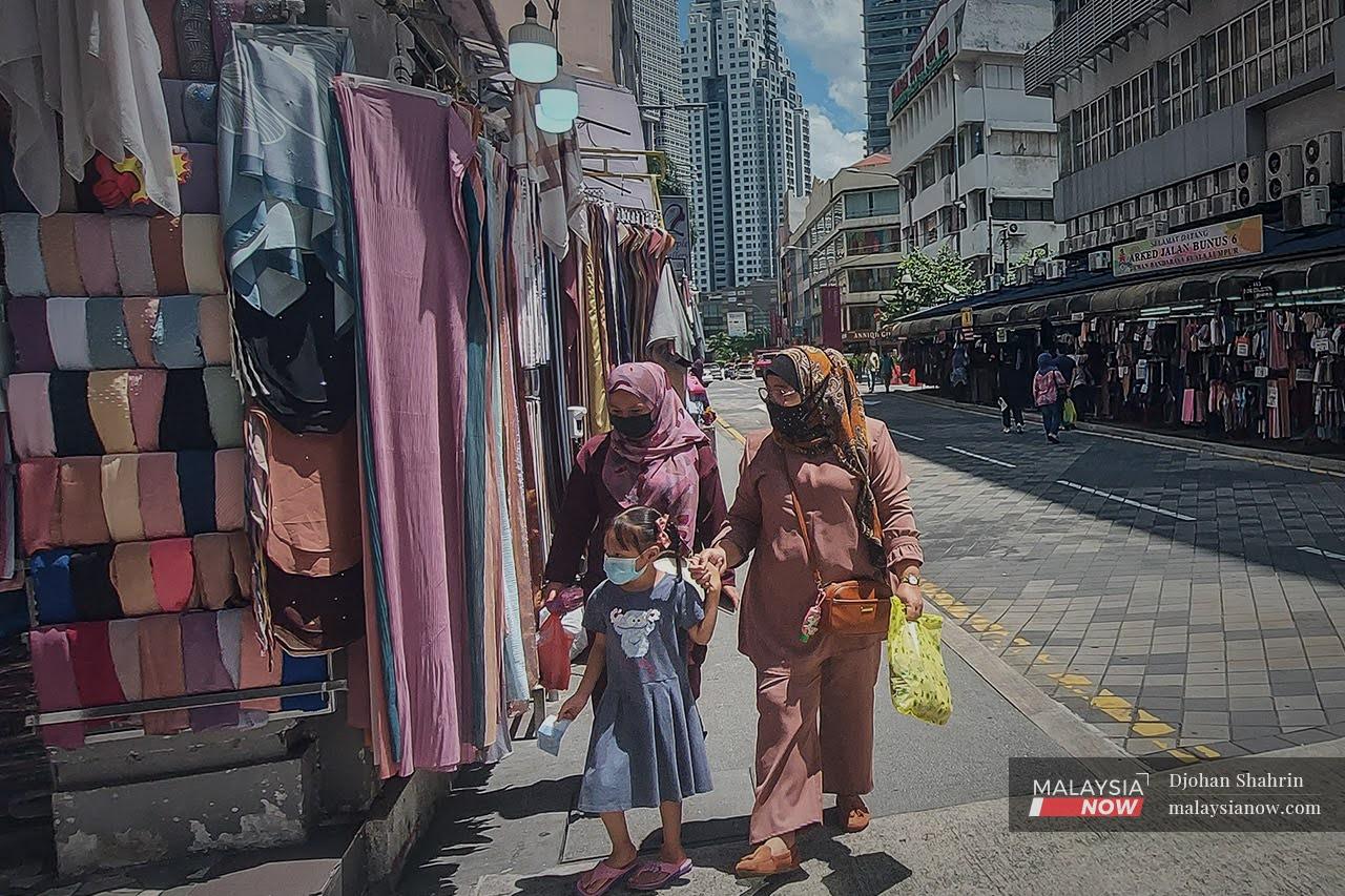 Pengunjung lengkap divaksinasi melihat barangan jualan semasa melalui Jalan Tuanku Abdul Rahman di Kuala Lumpur.
