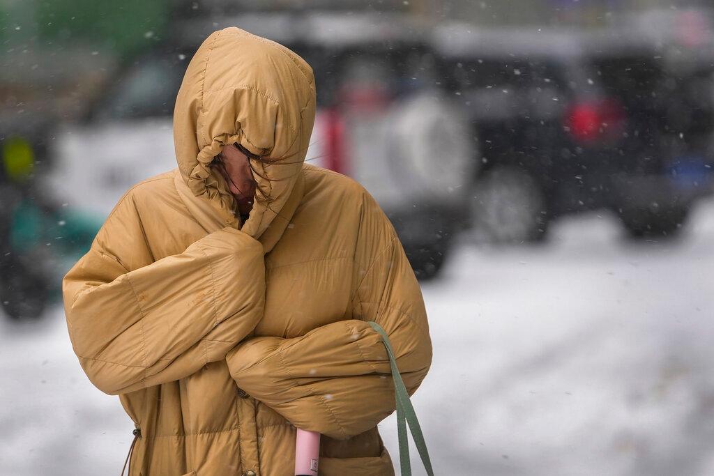 A woman uses her winter clothes to shield from the wind and snow on a street as the capital is hit by snowstorm in Beijing, Nov 7. Photo: AP