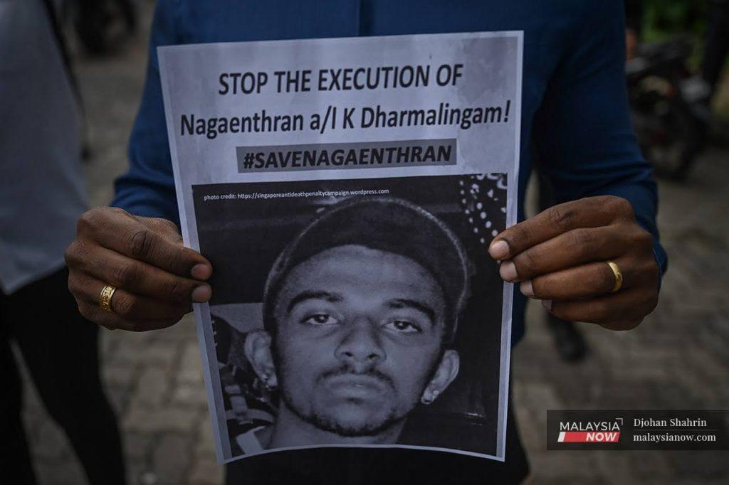 An activist holds up a poster showing Nagaenthran K Dharmalingam's picture at a gathering outside Parliament building last week.