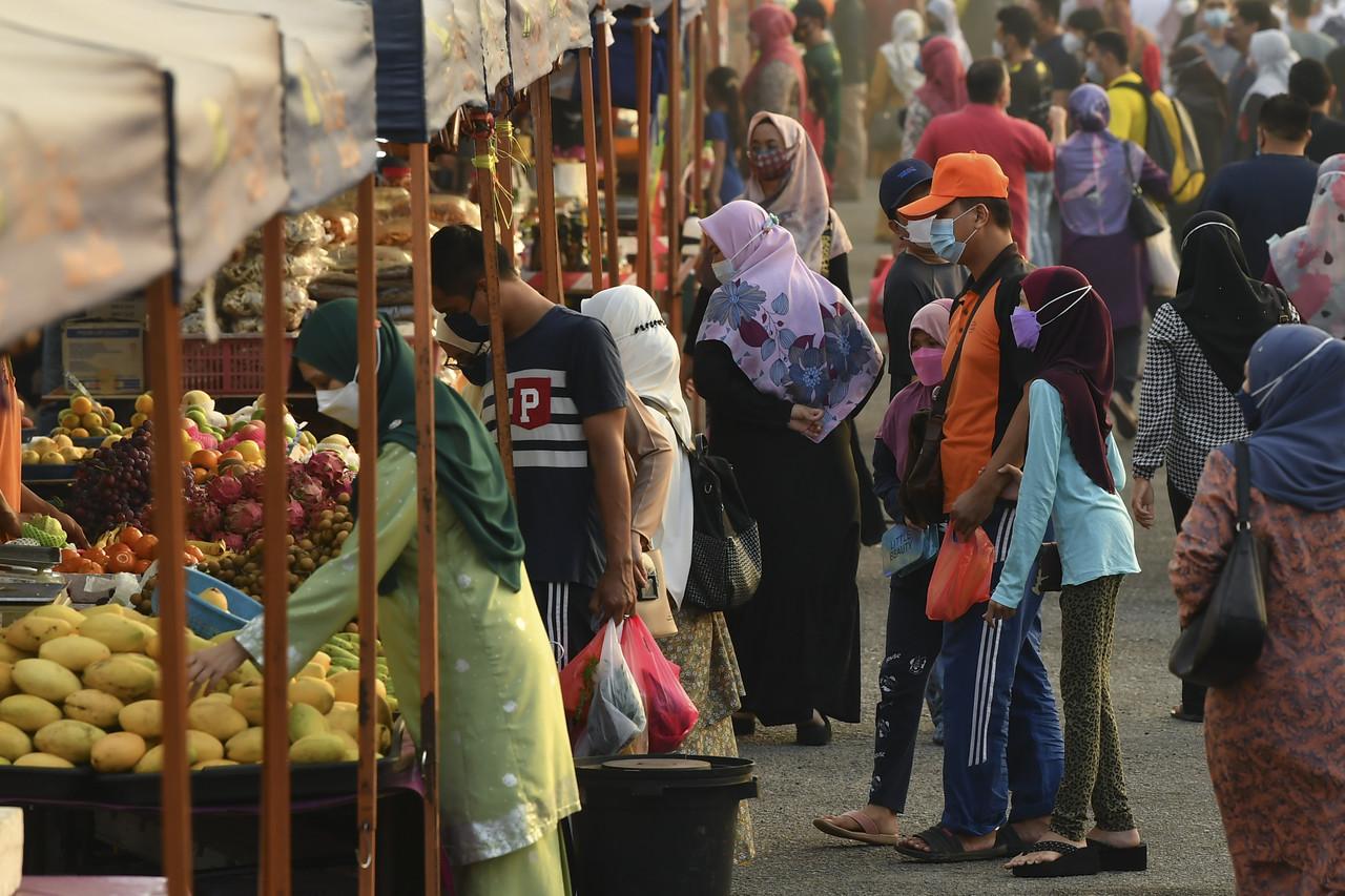 People wearing face masks to curb the spread of Covid-19 stop at a fruit stall at a farmers market in Putrajaya. Photo: Bernama