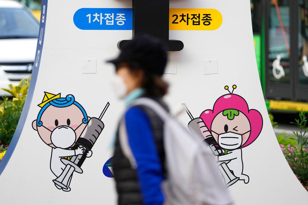 A woman wearing a face mask walks past a banner for Covid-19 vaccinations on a street in Seoul, South Korea, Nov 1. Photo: AP