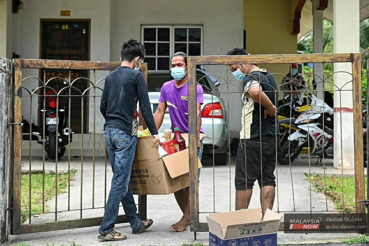 Ahli keluarga Orang Asli Temuan mengangkat barangan bantuan yang diberi kepada keluarga mangsa Covid-19 yang dikuarantin di Desa Temuan, Bukit Lanjan, Damansara Perdana.