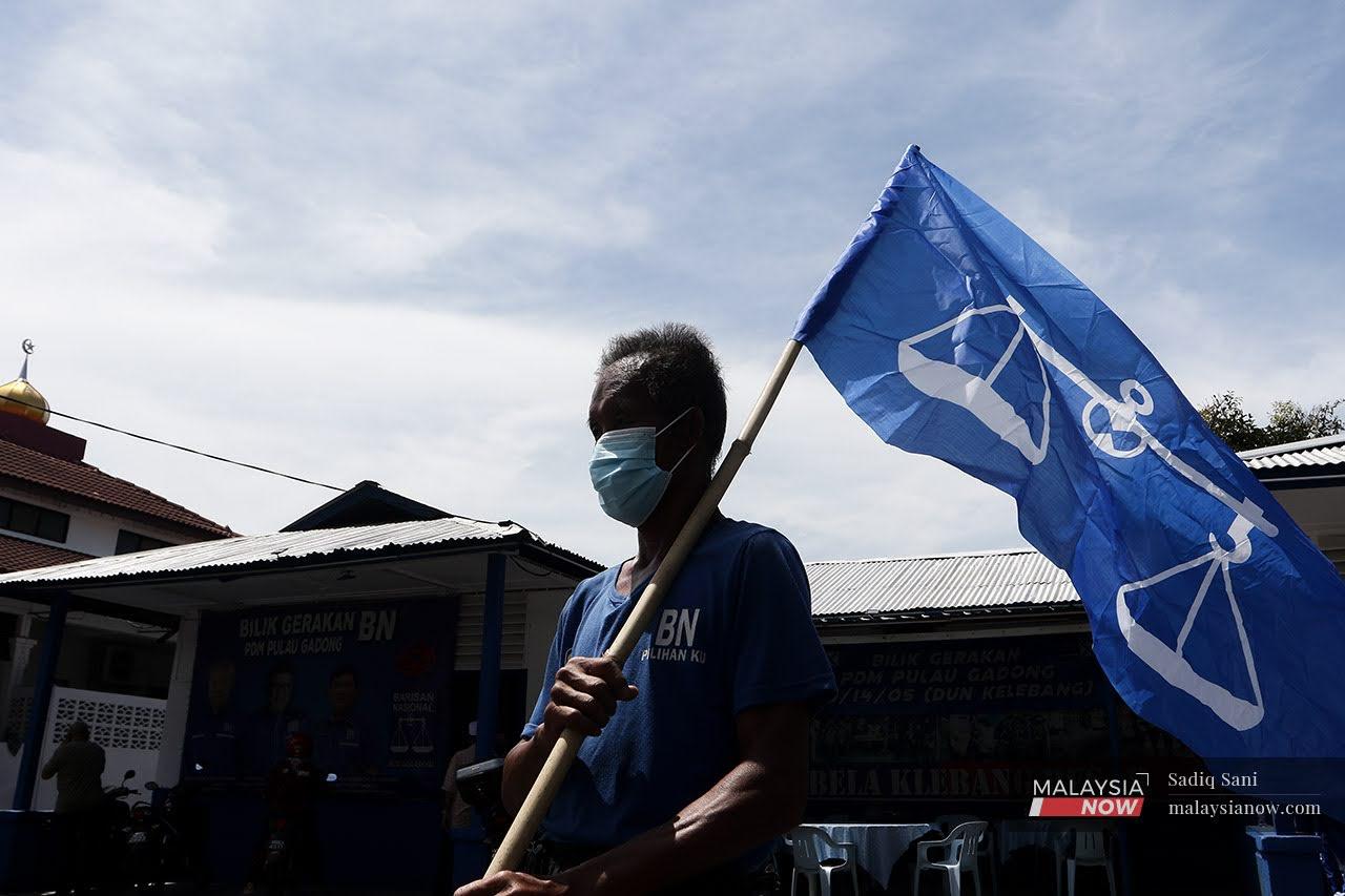 A man holds a Barisan Nasional flag in Kelebang Besar as the campaign continues ahead of the Melaka state election on Nov 20.