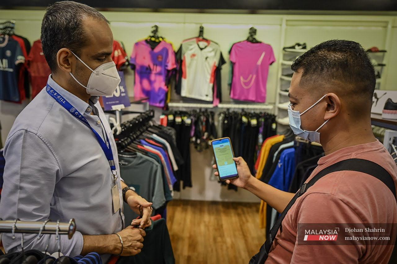 A customer shows his digital vaccination certificate at a sports apparel store in Jalan Tuanku Abdul Rahman in Kuala Lumpur. Proof of vaccination is needed for entry to many premises as the country transitions to the endemic phase of Covid-19.