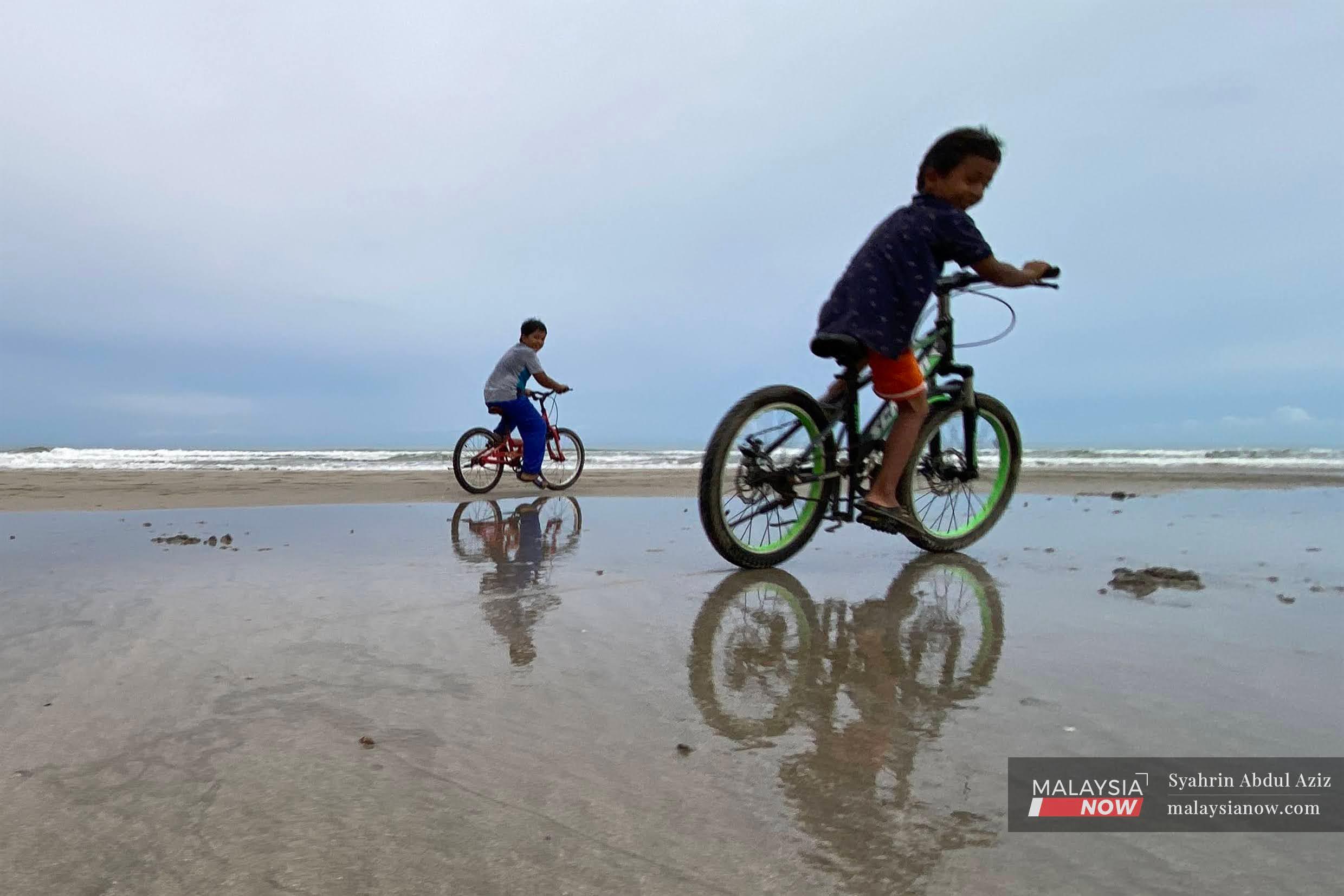 Dua kanak-kanak mengayuh basikal di  Pantai Beserah, Kuantan, Pahang.