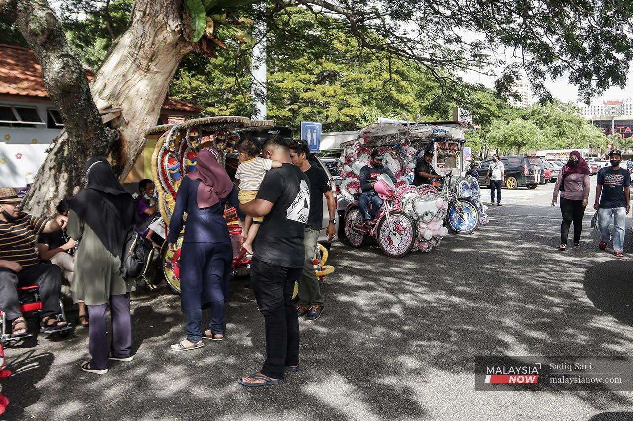 Rickshaw pullers wait for customers near Menara Taming Sari in Bandar Melaka.