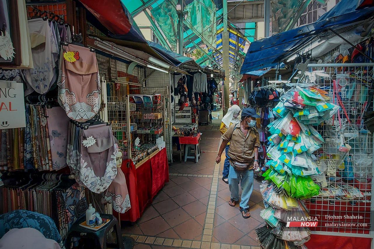 Pedestrians stop to look at the goods displayed on stalls in Jalan Masjid India, Kuala Lumpur.