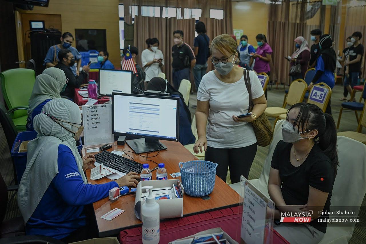 Parents and guardians wait to receive the digital vaccination certificate for their children at the KPJ Tawakkal vaccination centre in Jalan Pahang, Kuala Lumpur.