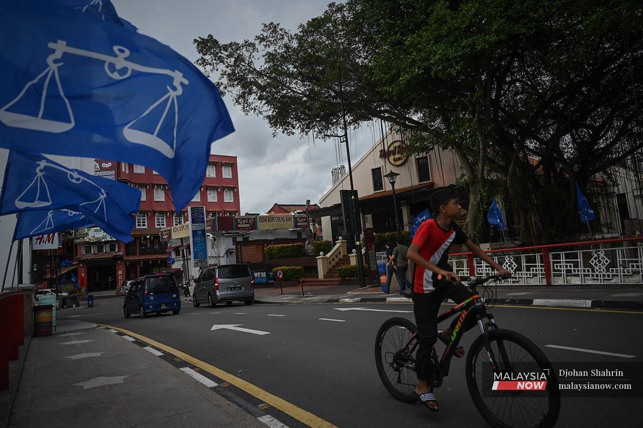 A youth cycles past a row of Barisan Nasional flags put up along Jonker Street ahead of the Melaka state election.