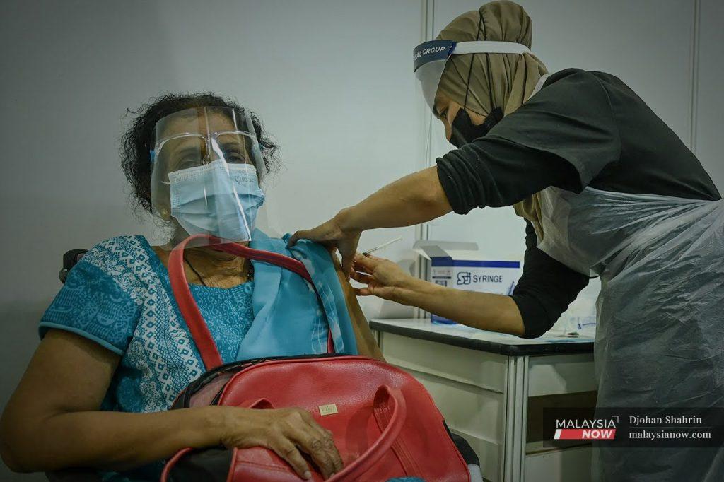 A health worker administers a dose of Sinovac vaccine to a woman at the Mitec vaccination centre in Kuala Lumpur in this file photo.