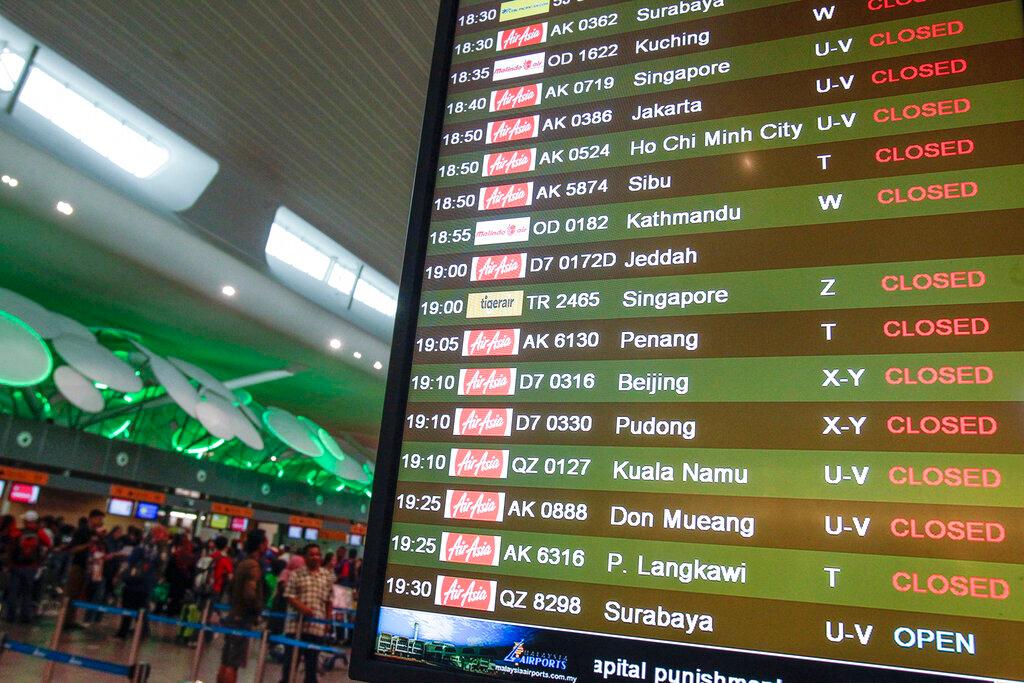 Travellers queue at counters as an information board shows AirAsia flight schedules at the klia2 airport in Sepang, in this Feb 8, 2015 file photo. Photo: AP