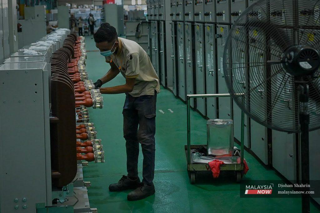 A worker adjusts equipment at an electrical and electronics factory in Kota Damansara, Selangor. Malaysia's chip assembly industry accounts for more than a tenth of global trade.