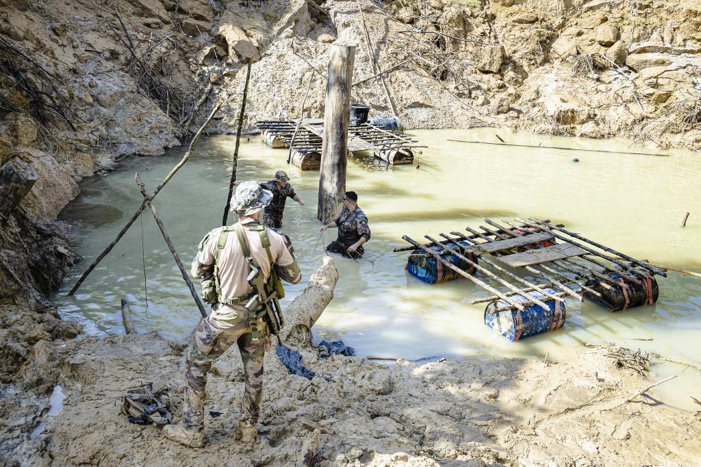 In this file photo taken on Oct 20, French soldiers search the bottom of a barranque in search of engines and pumps, submerged by artisanal miners before their escape after the soldiers discovered an illegal gold panning site on the Sparouine Cove during a mission against illegal gold panning in French Guiana. Photo: AFP