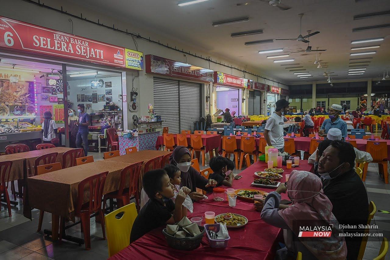 A family enjoys a meal at one of the stalls serving seafood set up at the Pernu-Umbai jetty in Melaka.
