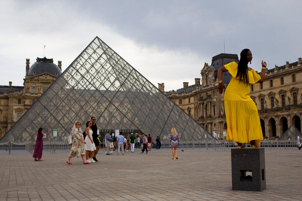 A woman poses for a photo in front of the pyramid of the Louvre museum, in Paris, June 18, 2019. In France, proof of vaccination or a recent negative test is required to go to restaurants, cafes and cinemas and to take long-distance trains, among other activities. Photo: AP