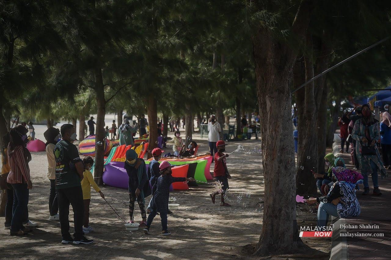 Children play with soap bubbles at the beach in Pantai Klebang, Melaka, as families enjoy a day out amid relaxed restrictions for domestic tourism.