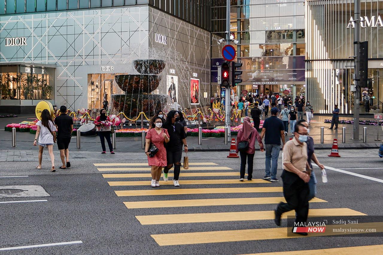 Pedestrians wearing face masks to curb the spread of Covid-19 cross a road in the Bukit Bintang shopping district of Kuala Lumpur.