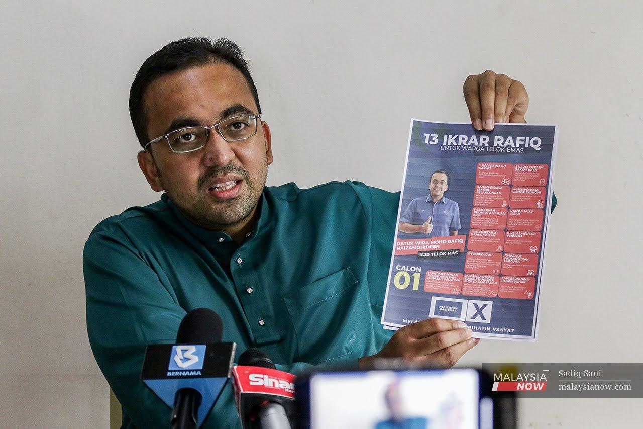 Melaka Perikatan Nasional chairman Mohd Rafiq Naizamohideen, the coalition's candidate in Telok Mas, holds up a paper showing his election pledges to voters at a press conference on Nov 18.