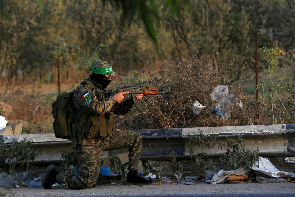 A masked militant from the Izzedine al-Qassam Brigades, a military wing of Hamas, takes a position to secure his colleagues marching along the main road of Nusseirat refugee camp, central Gaza Strip, Oct 28. Photo: AP