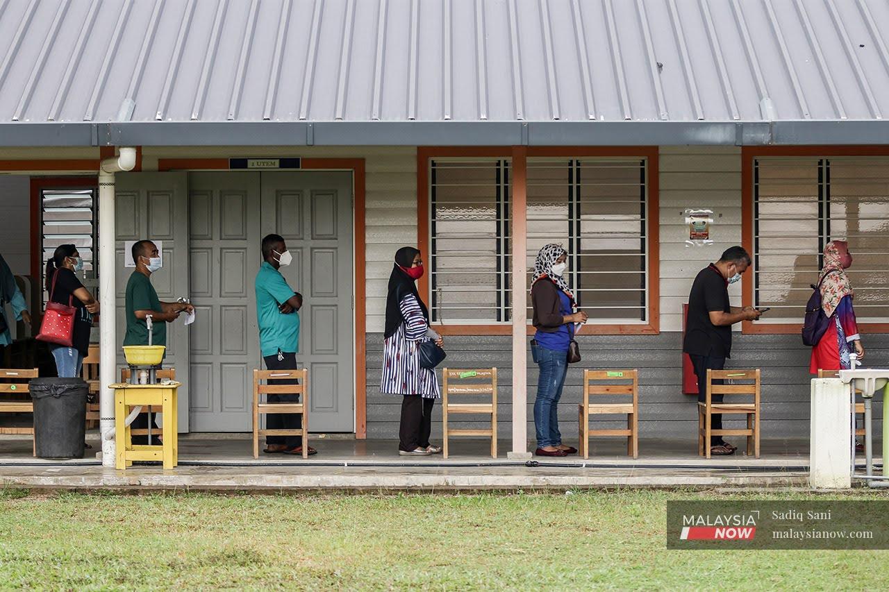 Voters wait in line at the polling centre at SK Durian Tunggal during the Melaka state election today.