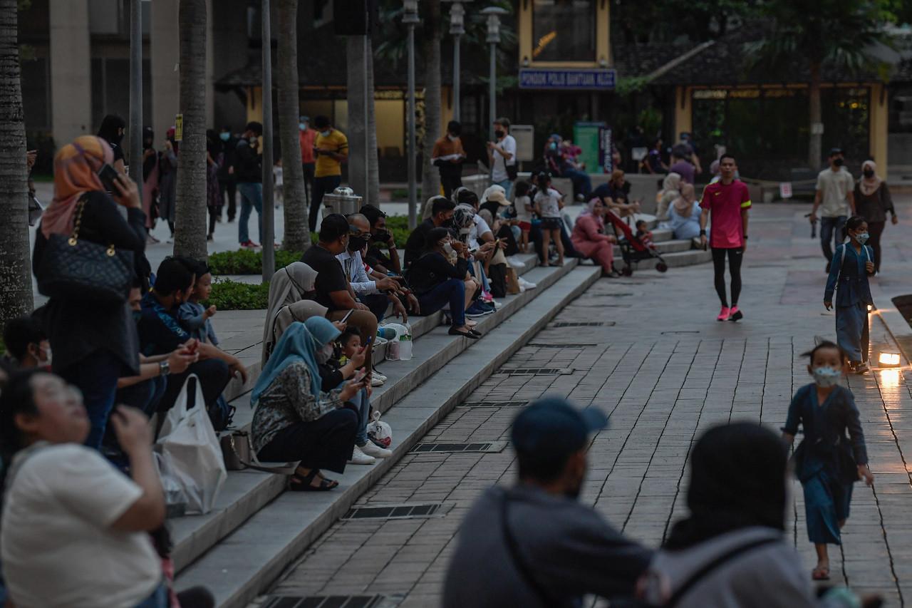 People mill about at Taman KLCC in Kuala Lumpur after work in the early evening. Photo: Bernama