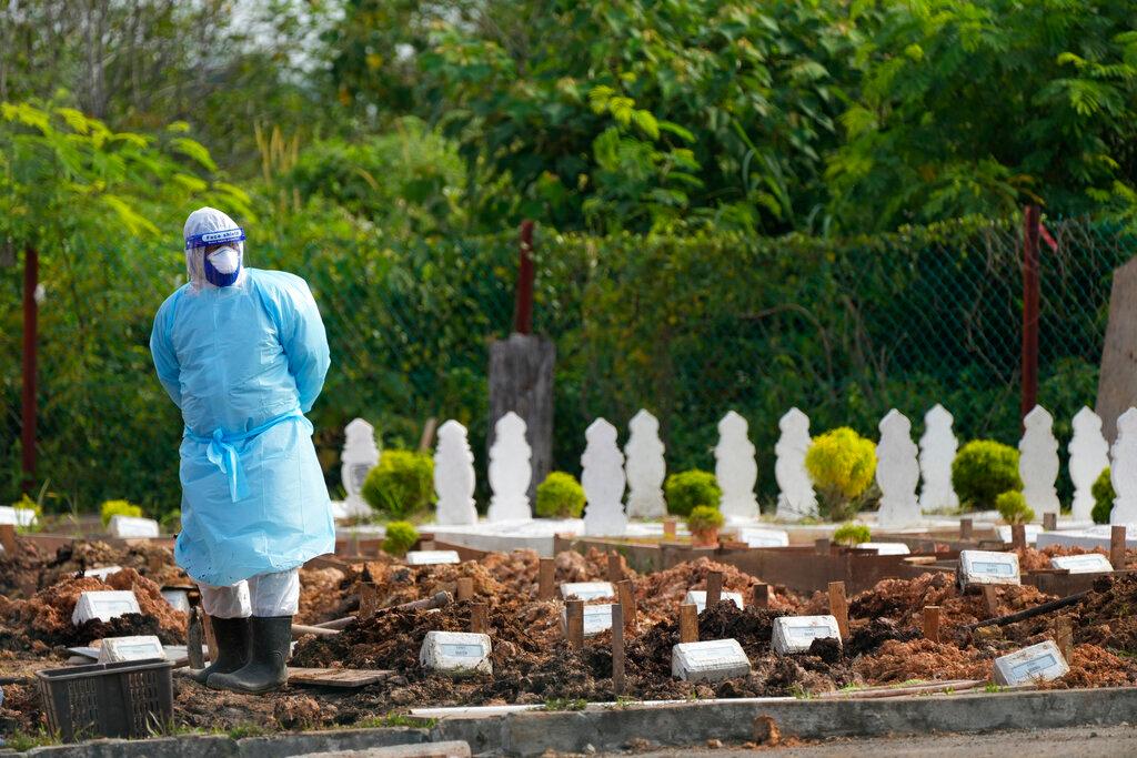 A health worker wearing personal protective equipment stands during a funeral procession for Covid-19 victims at a Muslim cemetery on the outskirts of Klang, Aug 27. Malaysia's Covid-19 death toll currently stands at 30,195. Photo: AP