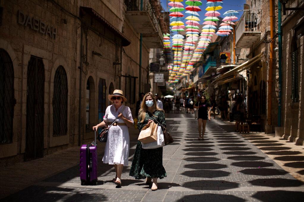 Women, one wearing a face mask, stroll along a street in Jerusalem in this July 16 file photo. Photo: AP