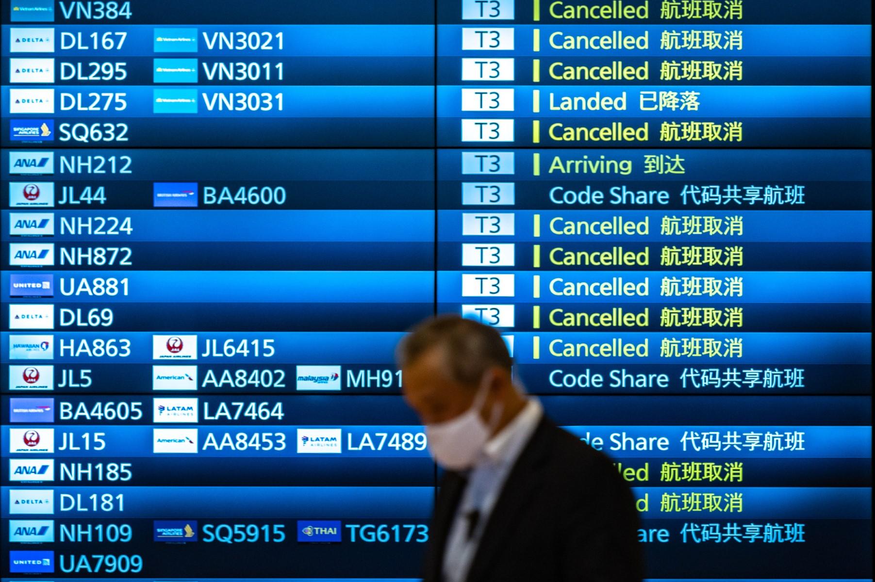 A man walks past an arrivals board showing cancelled flights at Tokyo's Haneda international airport on Nov 30, a day after Japan announced it would reinstate tough border measures, barring all new foreign arrivals over the Omicron Covid variant. Photo: AFP