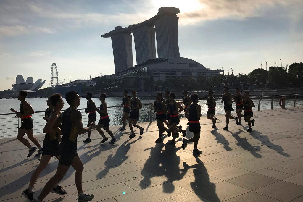 Runners are seen in silhouette and their shadows cast on the Marina Bay promenade as they jog at the start of a work day on Friday Aug 4, 2017, in Singapore. Researchers are testing a new bandage on patients with chronic venous ulcers, or leg ulcers caused by circulation problems in veins. Photo: AP
