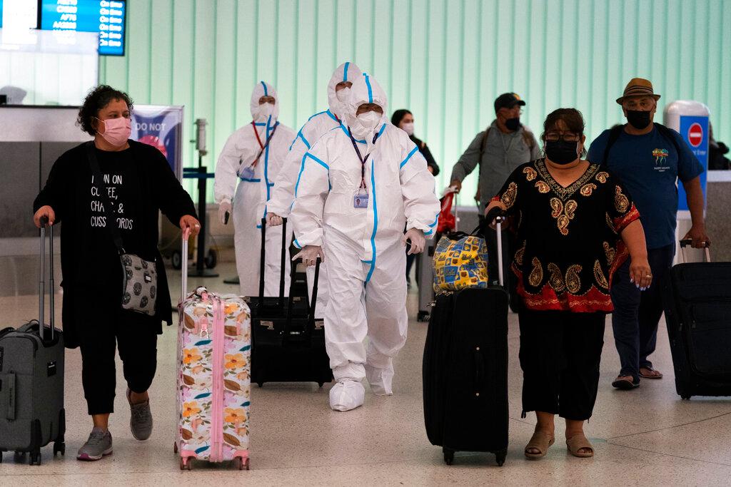 Air China flight crew members in hazmat suits walk through the arrivals area at Los Angeles International Airport in Los Angeles, Nov 30. Photo: AP