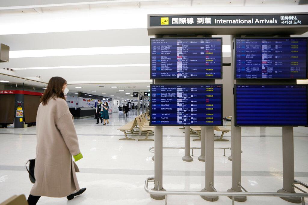A passenger walks by arrival information screens for international flights at the Narita International Airport in Narita, east of Tokyo, Dec 2. Photo: AP