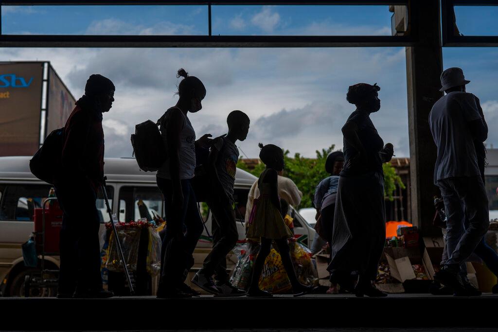Passengers, some wearing masks, line up to board a taxi at the Baragwanath taxi rank in Soweto, South Africa, Dec 2. Photo: AP