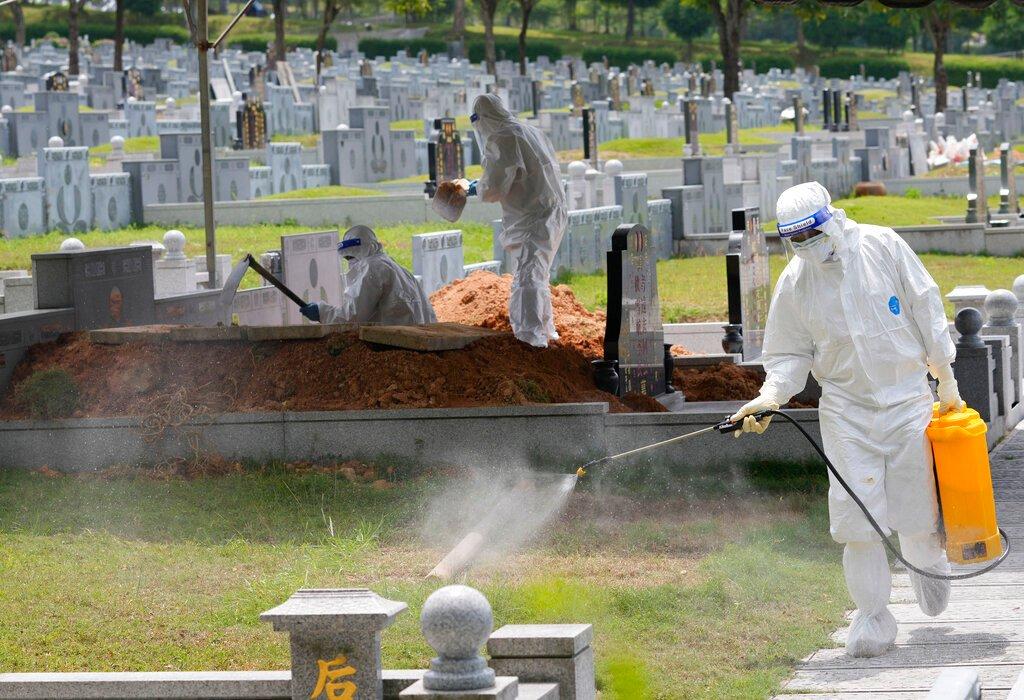 Petugas kesihatan memakai PPE lengkap ketika membersihkan kawasan semasa pengebumian mangsa Covid-19 di tanah perkuburan Nirvana, bagi penganut Buddha, Tao dan Kristian di Semenyih. Gambar: AP