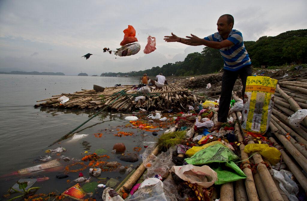A Hindu devotee throws flowers and plastic bags into river Brahmaputra in Gauhati, India, Oct 9, 2019. India generates about 3.4 million tonnes of plastic waste annually, according to official estimates. Photo: AP