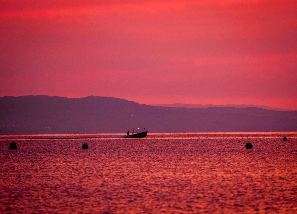 A fisherman drives his boat over the Lake Geneva in Geneva, Switzerland, before sunrise, June 17. Authorities said 1,600 of those quarantined in Vaud and Geneva were children. Photo: AP