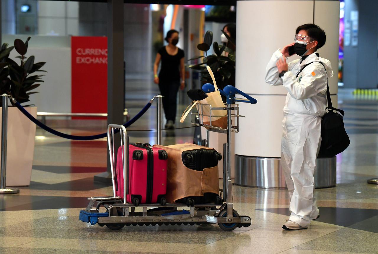 A passenger wearing a face mask speaks on her phone upon her arrival at KLIA in Sepang, Dec 3. Photo: Bernama