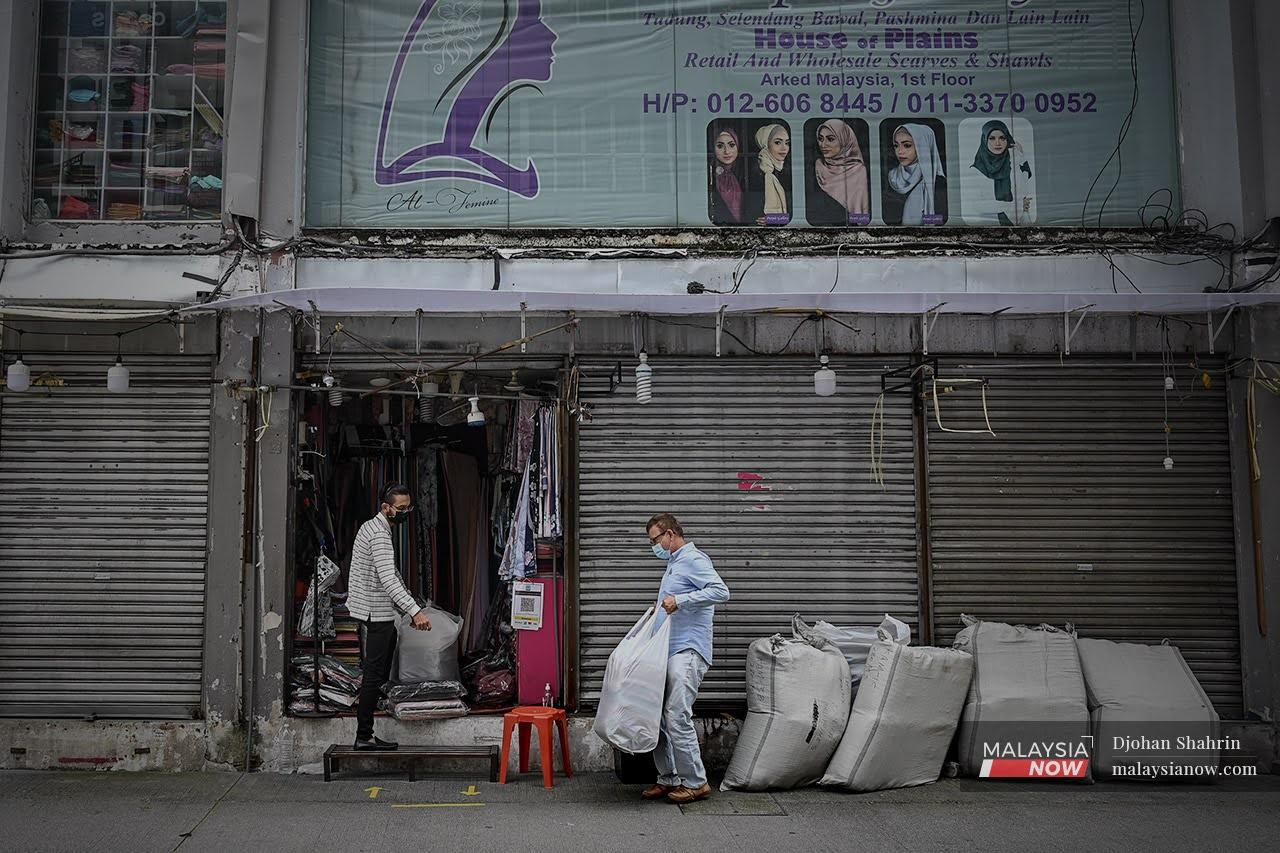 Pekerja mengangkat stok bungkusan barangan niaga dan menyimpan di sebuah kedai terletak di Jalan Tuanku Abdul Rahman.