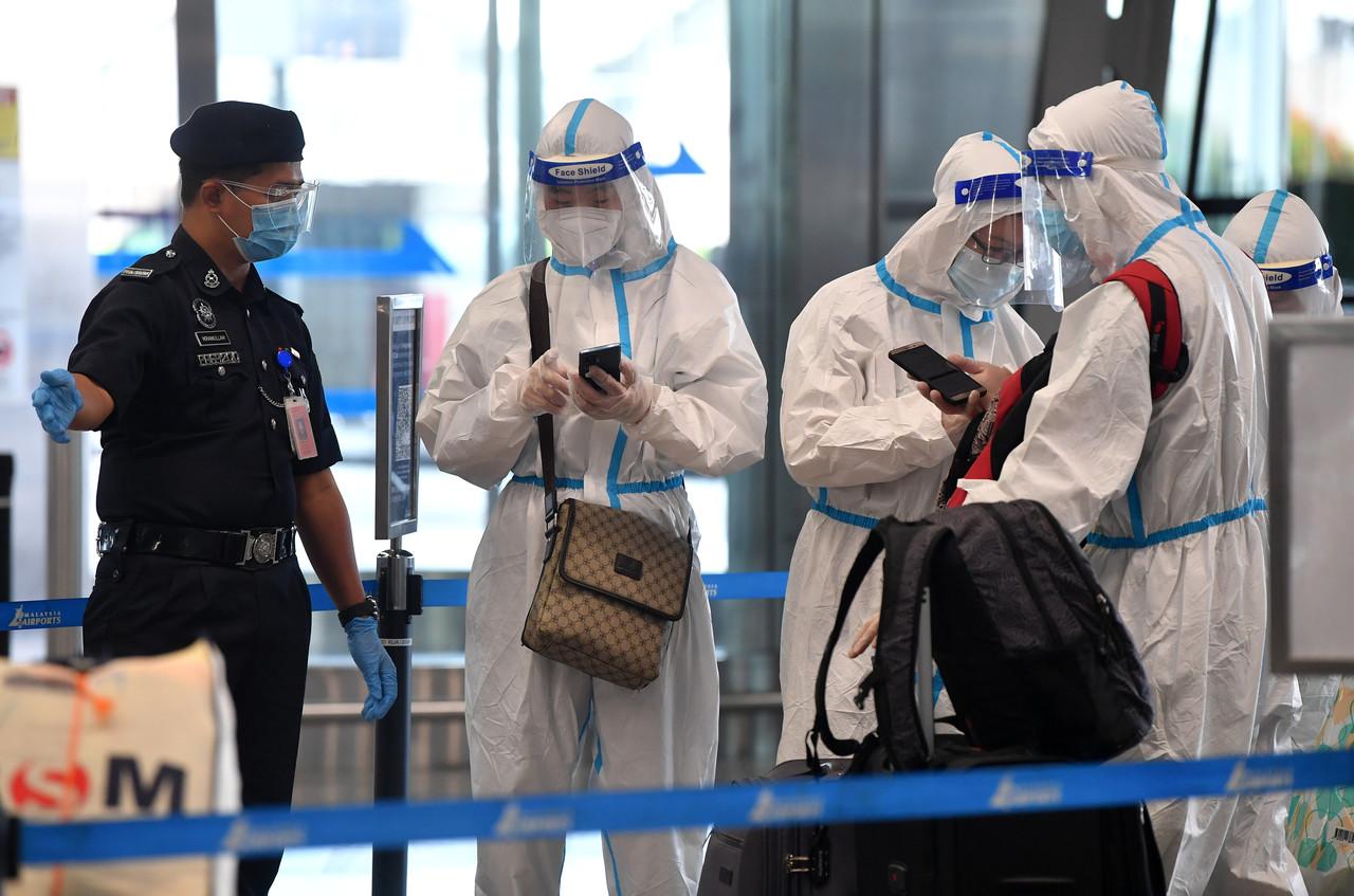 A police officer directs passengers dressed in full personal protective equpiment at KLIA in Sepang amid concerns over the Omicron Covid-19 variant. Photo: Bernama