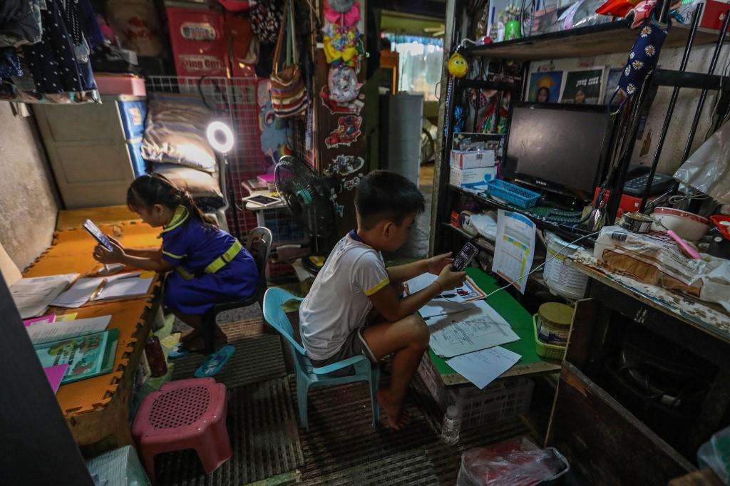 Two children start their online learning from home using mobile phones and printed modules in Mandaluyong city suburban Manila on Oct 5, 2020. The disruptions are not being felt equally, with the study finding that poorer and disabled children have less access to remote learning, while younger students were overall more affected. Photo: AP