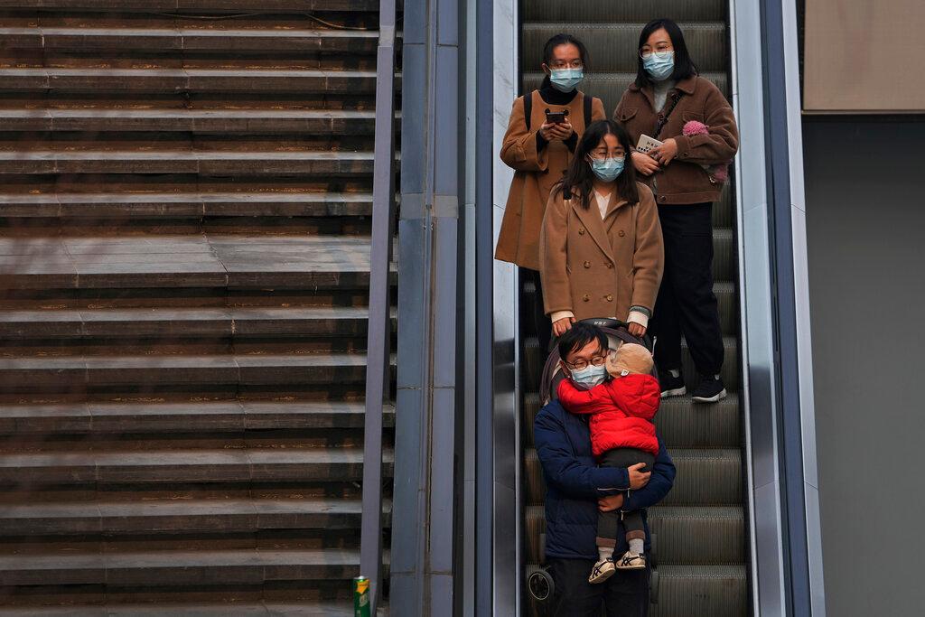 People wearing face masks to protect from Covid-19 take an escalator at a commercial office building in Beijing, Nov 28. The IMF is pushing the G20 group of the world's richest countries, including China, to extend and improve their debt relief initiative, warning that many countries face a dire crisis without the help. Photo: AP