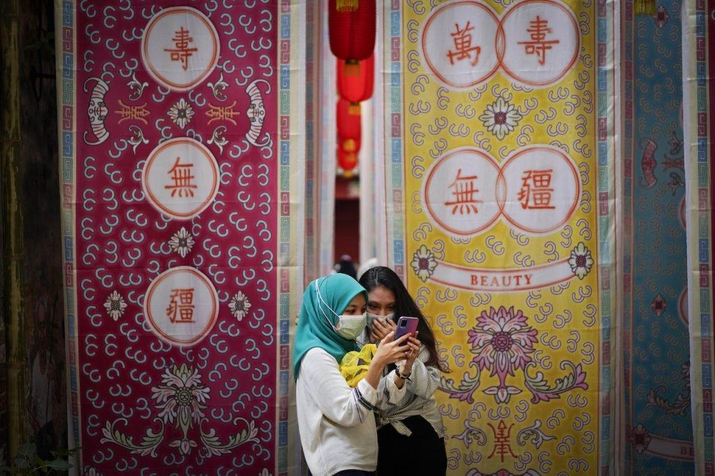 Seorang gadis berlitup muka menatal telefon pintar di Kwai Chai Hong, Jalan Petaling, Kuala Lumpur. Gambar: AP