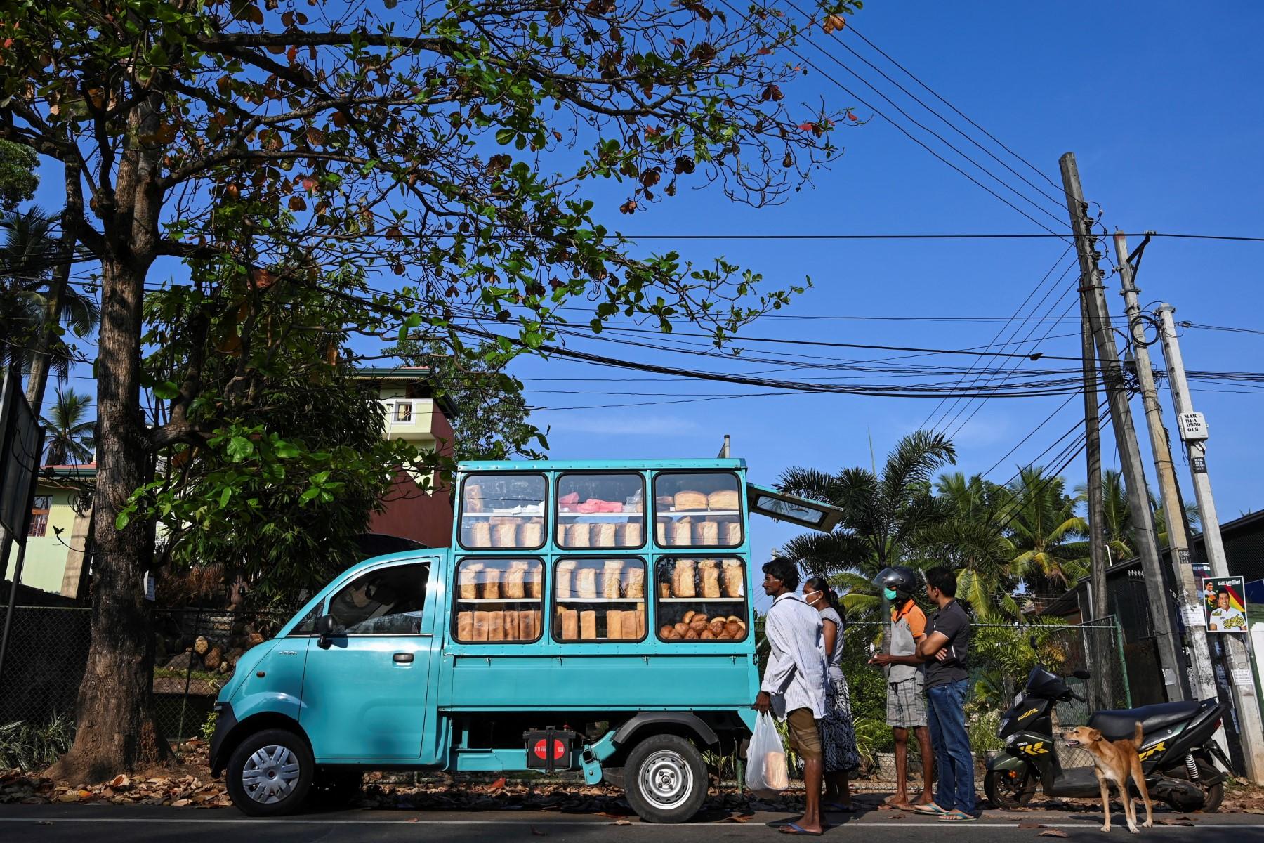 People buy bread from a vendor on a street in Colombo in this March 27, 2020 file picture. Gas cylinders are a common source of energy for cooking in Sri Lanka, especially in rural areas. Photo: AFP