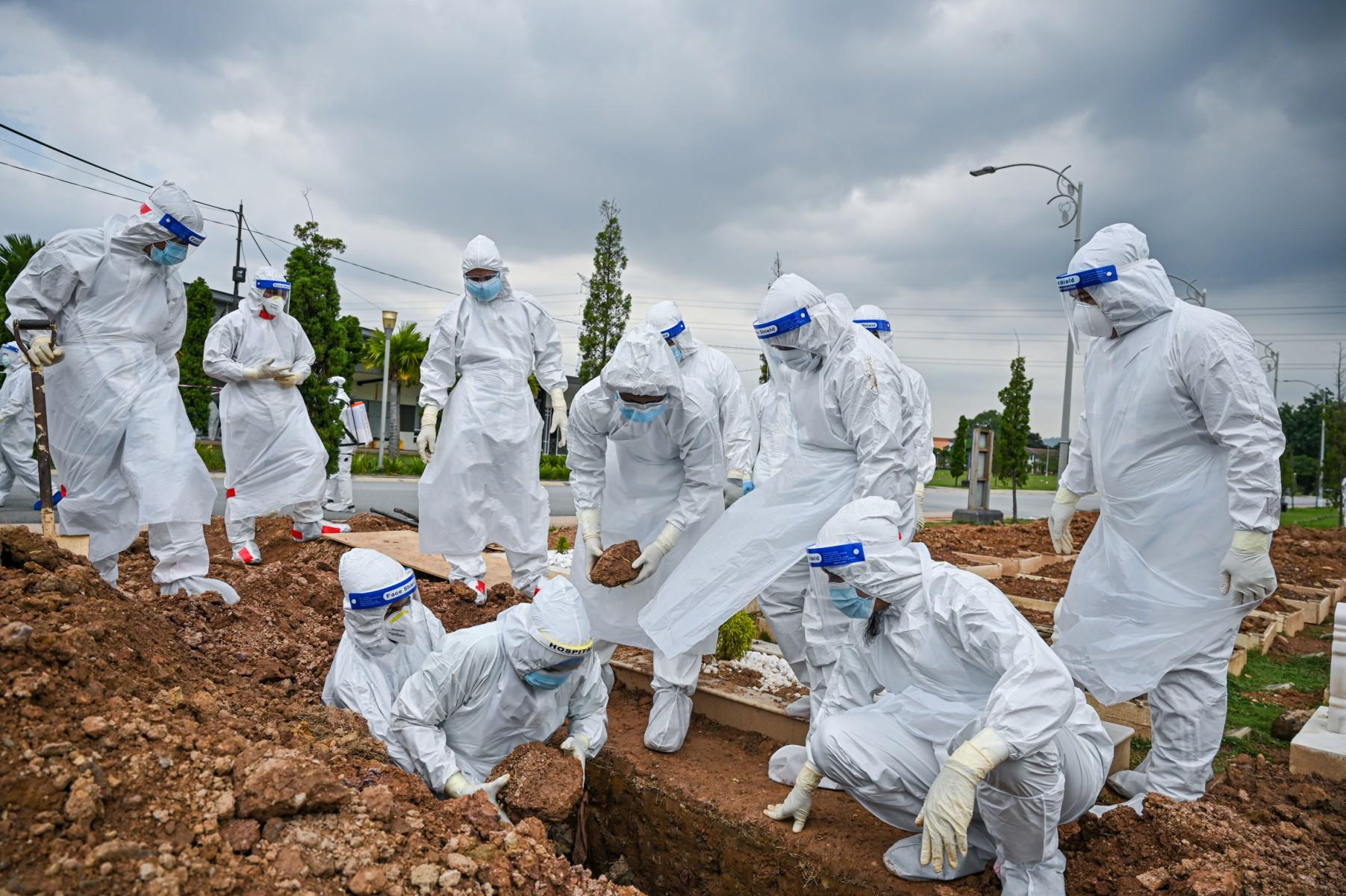 Volunteers wearing protective suits bury a Covid-19 victim at a cemetery in Kuala Lumpur on June 15. Photo: AFP