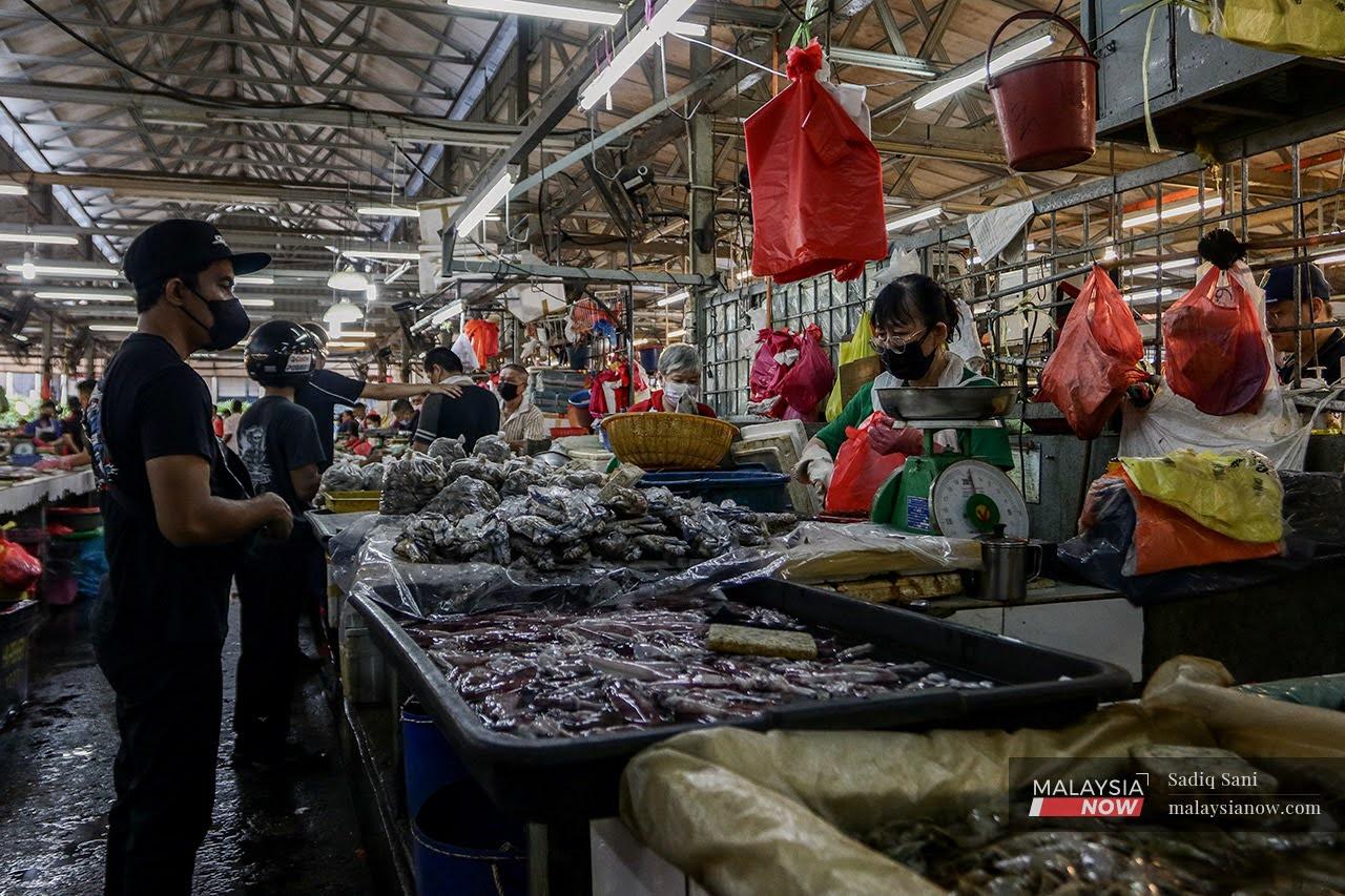 A fishmonger packs a customer's order at the Raja Bot market in Kuala Lumpur.