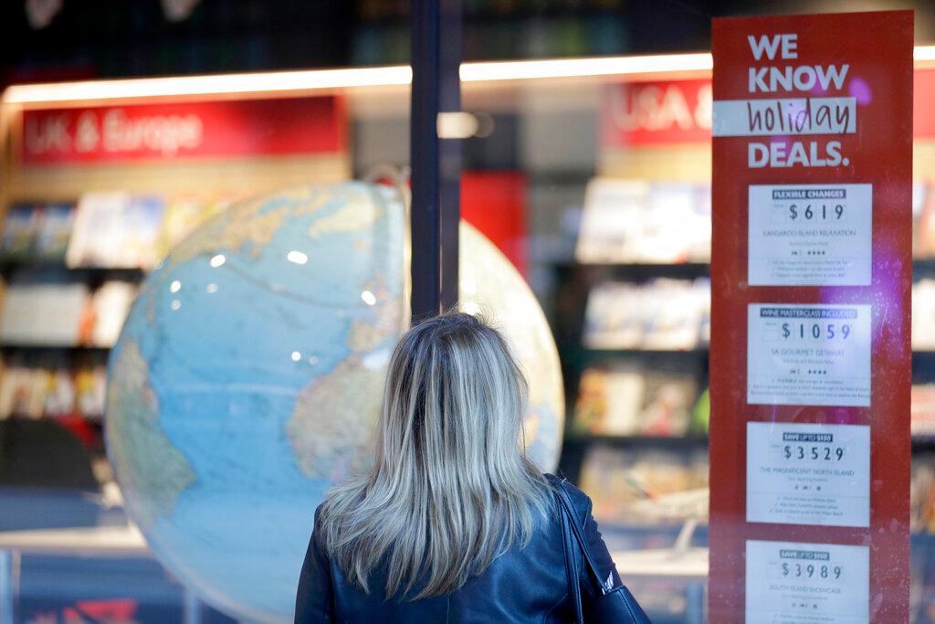 A woman looks at ads in the window of a closed travel agent office in Sydney, on Aug 13. Photo: AP