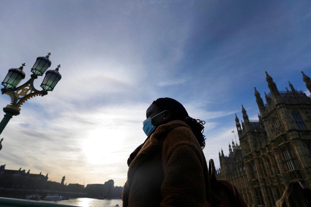 A woman wears a face covering as she crosses Westminster Bridge in London, Dec 9. Photo: AP