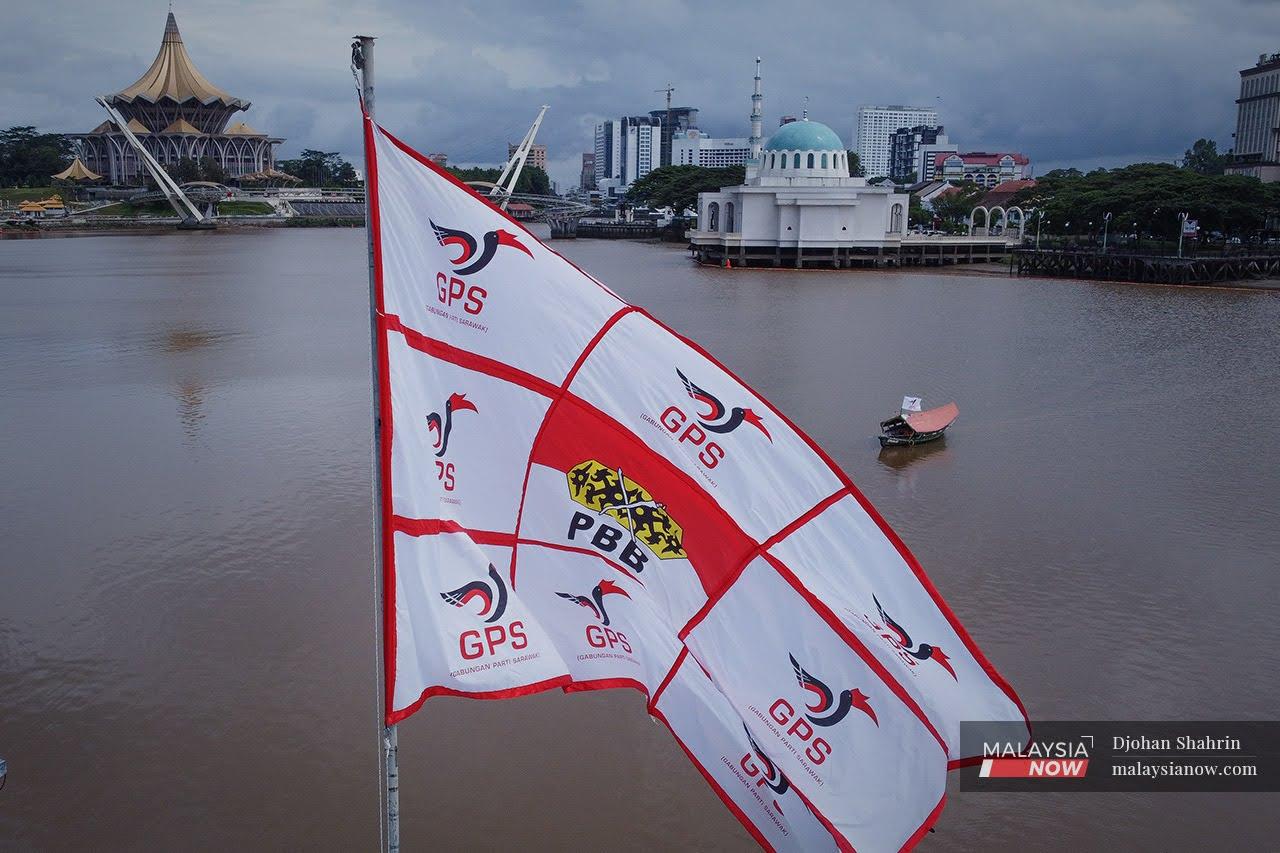 A giant flag showing the logos of Gabungan Parti Sarawak and its component Parti Pesaka Bumiputra Bersatu flutters across the river from the state legislative assembly building in Kuching.