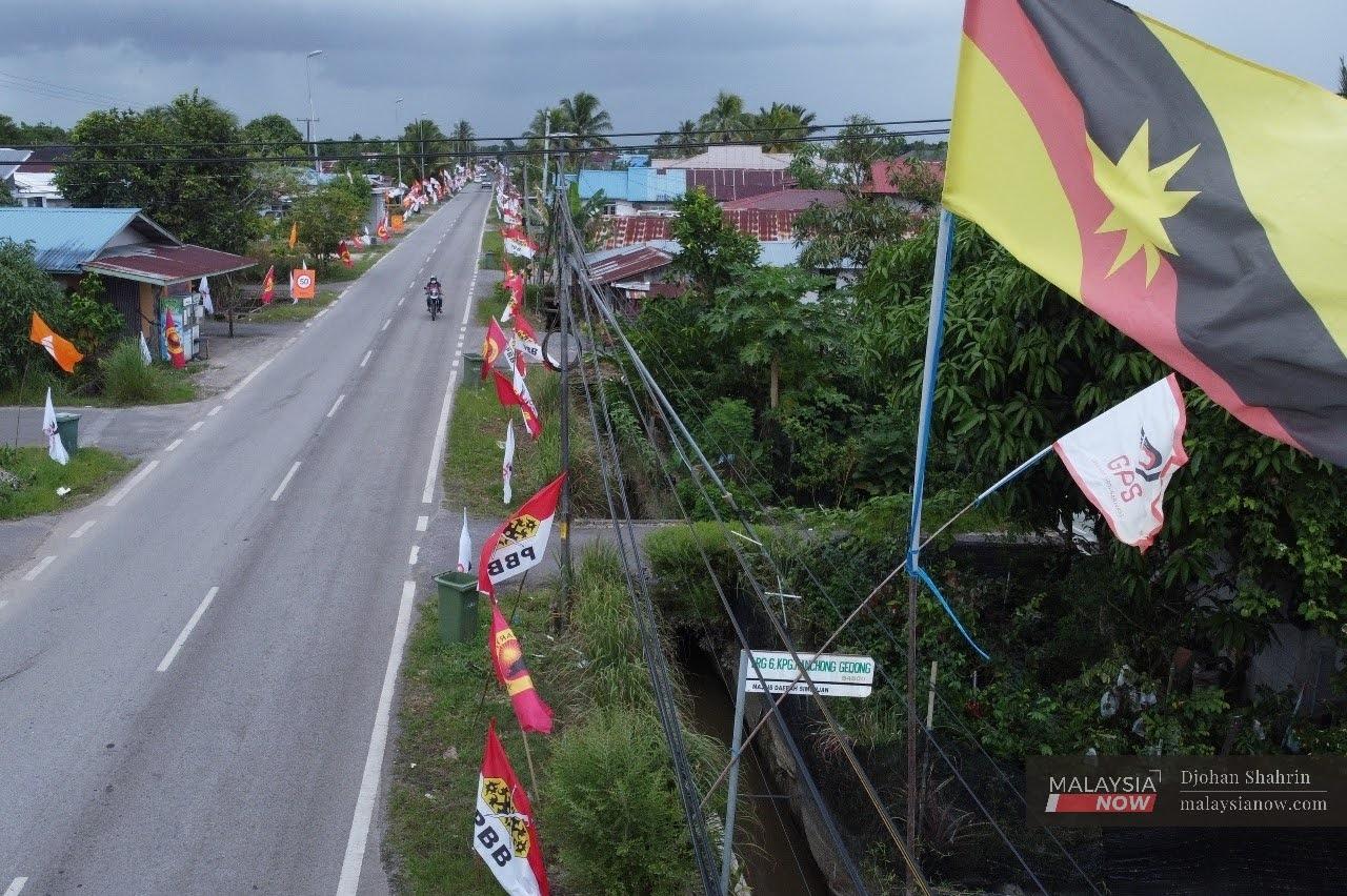 A motorcyclist makes his way down a road decked out with party flags ahead of the Sarawak state election on Dec 18.