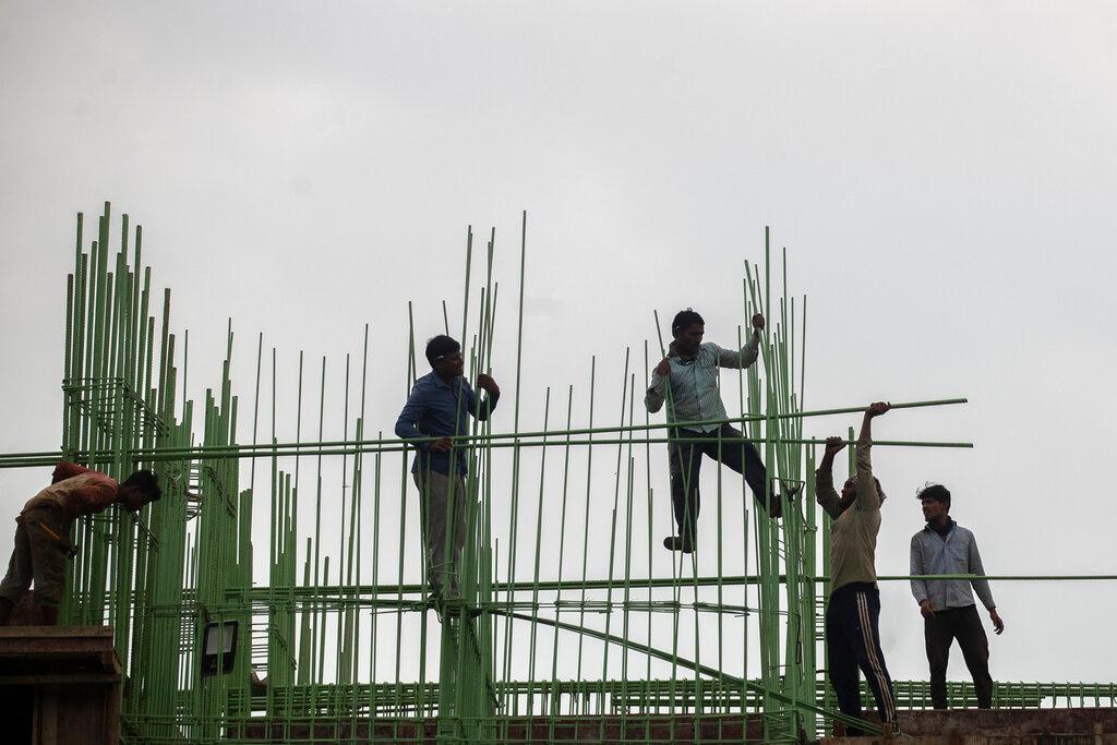 Labourers work at a building construction site in Mumbai, India, Nov 30. Indian national Sudesh Kumar has been arrested for murdering a builder and passing the body off as his own in an attempt to fake his own death. Photo: AP